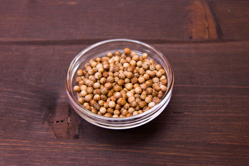 Coriander seeds on a bowl on a wooden table