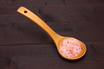Wooden spoon with pink Himalayan salt on a wooden table