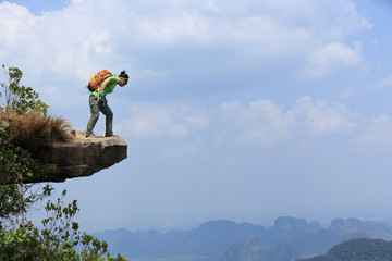 successful woman hiker enjoy the view at mountain peak cliff