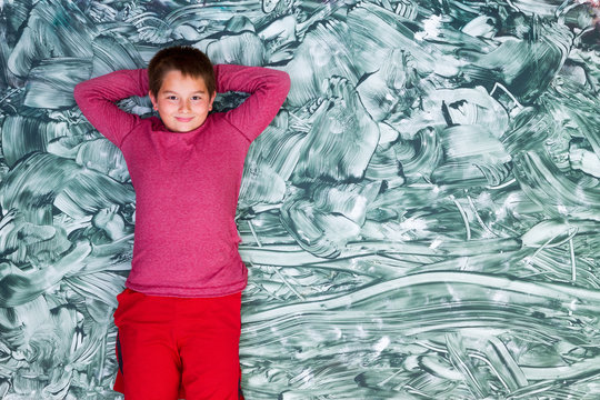 Cute tween boy relaxing on large green painting
