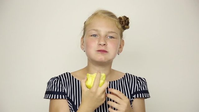 beautiful young girl dressed in a striped dress eating an apple. healthy food - strong teeth concept