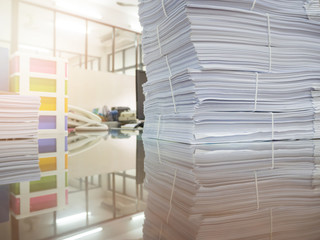 Pile of unfinished documents on office desk with businessman background