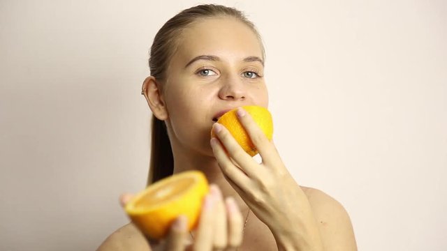beautiful naked young woman eating an orange. healthy food - strong teeth concept