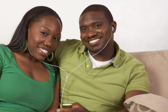 Happy young ethnic black couple listening music