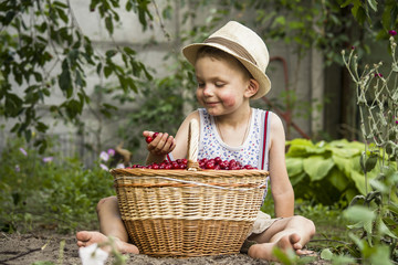 Boy with a basket of cherries in the garden