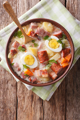 Zurek soup with smoked meat close up on the table. Vertical top view
