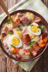 Delicious Polish soup Zurek with sausage and eggs in a bowl. Vertical top view
