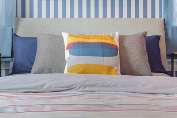 Yellow and blue graphic print pillow setting on stripe bedding bedroom
