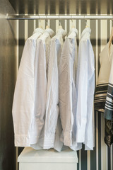 Row of white shirts hanging in retro style background wardrobe