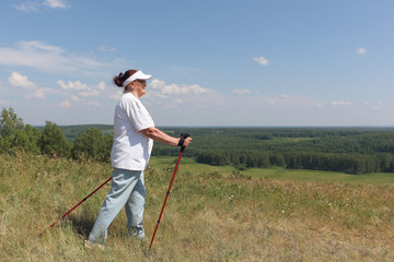 Nordic Walking - elderly woman is hiking  in the summer