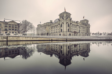 Fototapeta na wymiar Reichstag building (Bundestag) and with reflection in river Spree in Winter, Berlin government district, Germany, Europe, Vintage filtered style
