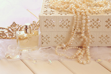 Fototapeta na wymiar White pearls necklace, diamond tiara and perfume bottle