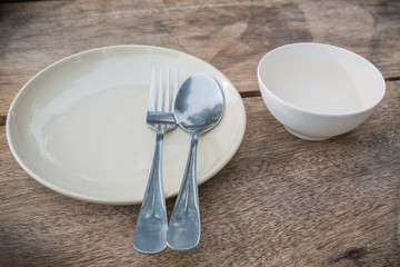 Fork, spoon and cream dish on wooden table close up view.