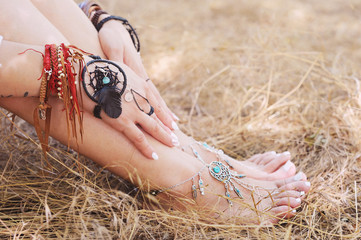 Handcrafted bracelets on a woman legs and hands, dreamcatcher jewelry