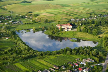Fototapeta na wymiar Countryside aerial view on old castle with red roof over the lake