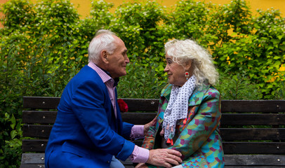 Elderly man and  woman sitting on a bench talking.