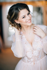 Fototapeta premium girl in boudoir gown with a smile on his face corrects hairstyle