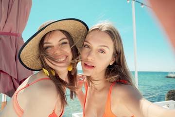 two smiling young women on beach making selfie
