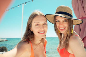 two smiling young women on beach making selfie