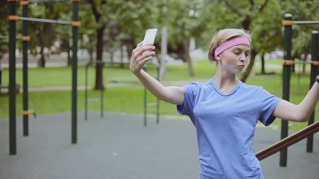Portrait of a young sporty woman smiling and taking a selfie while training in public playground