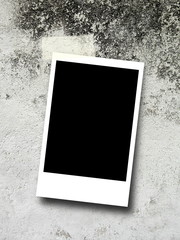 Close-up detail of one blank black rectangular instant photo frame with adhesive tape on gray concrete wall background