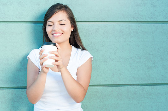 Young Woman Holding And Looking At Takeaway Coffee