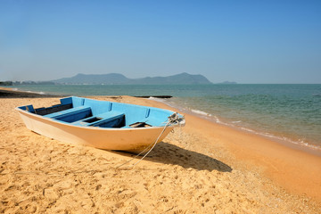 Fishing boat on sand with blue sky