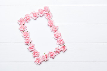 Pink rose frame over white wooden background