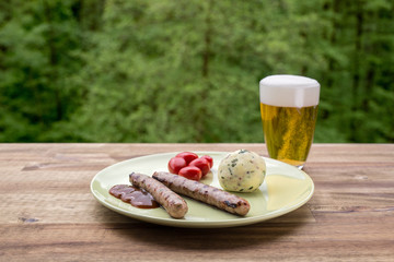 Im Biergarten. Zwei Grillwürste angerichtet auf grünem Teller mit Cherrytomaten und...