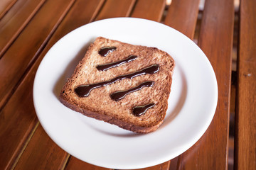 Chocolate Spread on Toast in white disk on wood table