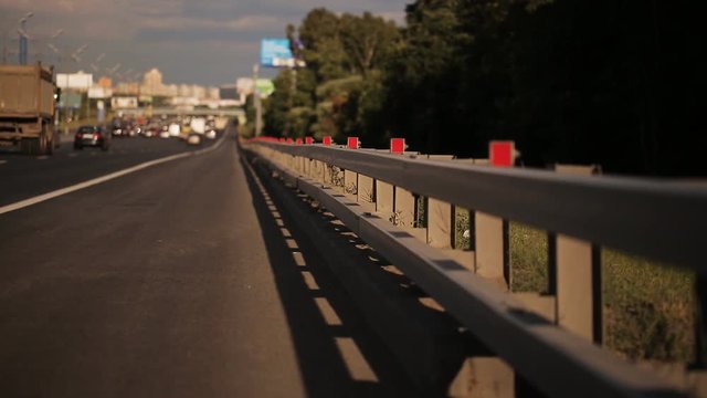 Movement of cars on highway in Sunny day. Roadside in area of focus, and the road blurred.