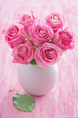 Beautiful fresh roses flowers in a vase on a pink background.
