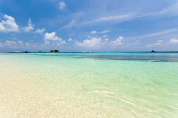 Beautiful tropical beach with palm trees, white sand, turquoise ocean water and blue sky at Kuredu, Maldives