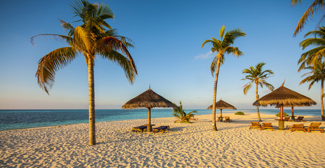 Beautiful tropical beach with palm trees, white sand, turquoise ocean water and blue sky at Kuredu, Maldives