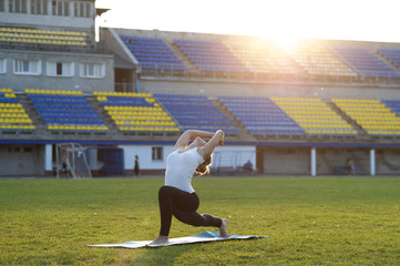 Young flexible woman practicing yoga in park