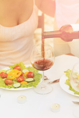 Toned picture of sommelier pouring red wine in the glass. Professional sommelier pouring red wine for beautiful woman in restaurant or cafe.