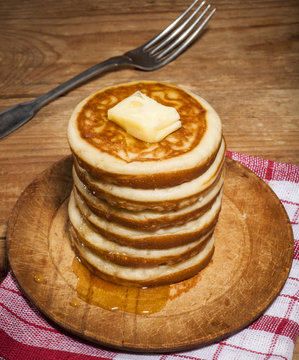 Pancakes with honey and butter on wooden background