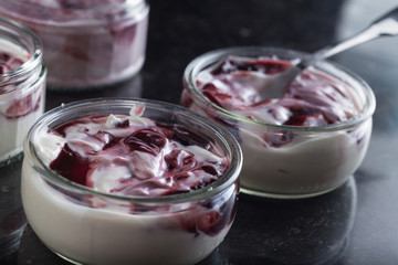 Yogurts with fruits assortment in glass bowls on dark marble background. Natural and fruit healthy, diet, gourmet dessert for granola breakfast. Sweet yoghurts closeup.