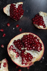 Red juicy pomegranate on dark marble background. Healthy, antioxidant, fresh, gourmet, delicious, organic fruit. Ingredient for grenadine. Close-up and copy space.
