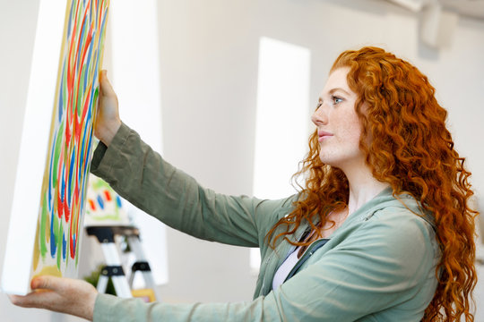 Young caucasian woman standing in art gallery front of  paintings