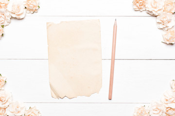 Old paper sheet with empty copyspace and roses on white table