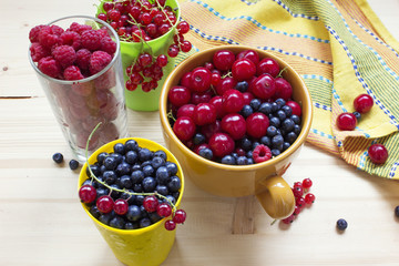 Assorted berry on a wooden table: cherries, blueberries, currants, raspberries.