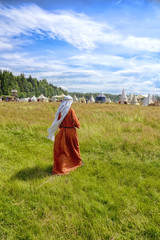 the woman in a medieval dress goes on a grass