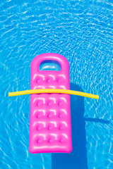 Pink air bed floating on a swimming pool