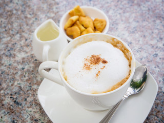 White cup of cappuccino stands on the rock table, selective focus