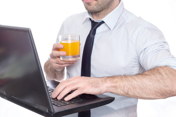 man typing holding a juice glass