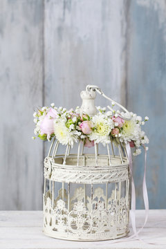 Vintage bird cage decorated with wreath made of pink ranunculus