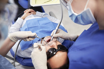 Fototapeta premium female dentist treating male patient teeth