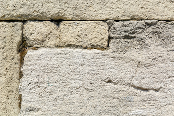 gray wall of sandstone blocks of rectangular shape with uneven edges