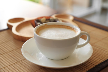 Cup of coffee on wooden table with confectioners atmosphere.